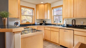 A modern kitchen with wooden cabinets, a granite countertop, and a built-in dishwasher. - Sawmill Station 220 | Private Hot Tub | Walk To Shops & Dining (Winter Park)