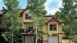 A two-story house with a covered porch and a garage. - Sawmill Station 220 | Private Hot Tub | Walk To Shops & Dining (Winter Park)