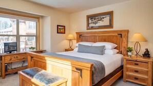 A bedroom with a wooden bed, bedside tables, a desk, and a window. - Sawmill Station 220 | Private Hot Tub | Walk To Shops & Dining (Winter Park)
