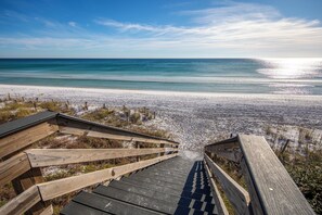 A wooden staircase leading to a beach with a clear view of the ocean.