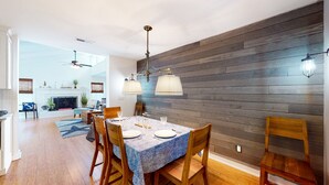 Een eethoek met een houten wand, een open haard en een plafondventilator.
