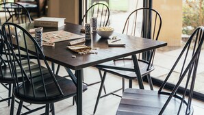 A dining table with chairs, a bowl of popcorn, a can of soda, and a Scrabble game set on it. - Firefly by AvantStay | Spacious Backyard w/ Pool& Hot Tub! (La Quinta)