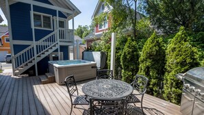 A wooden deck with a hot tub, outdoor seating, and a grill. - Cozy Couples Retreat in Beachwalk Resort w/ Hot Tub (Michigan City)