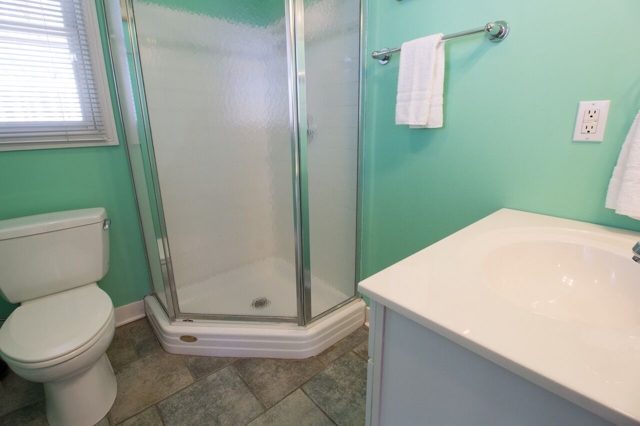 A bathroom with a toilet, a glass-enclosed shower, and a sink.