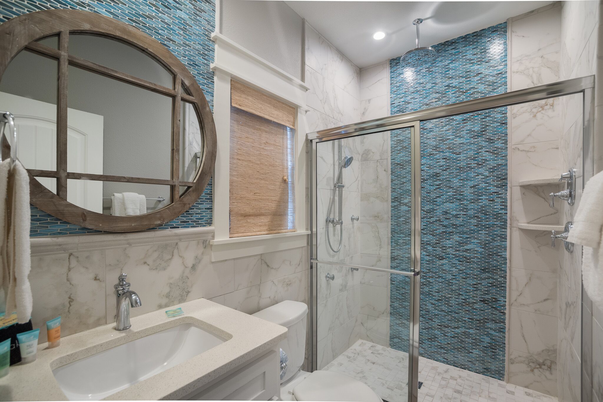 A bathroom with a glass-enclosed shower, a sink with a mirror, and a toilet.