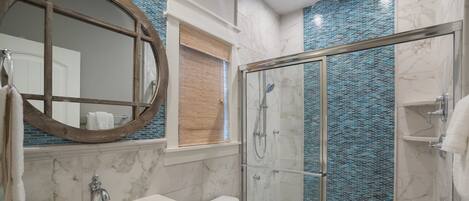 A bathroom with a glass-enclosed shower, a sink with a mirror, and a toilet.