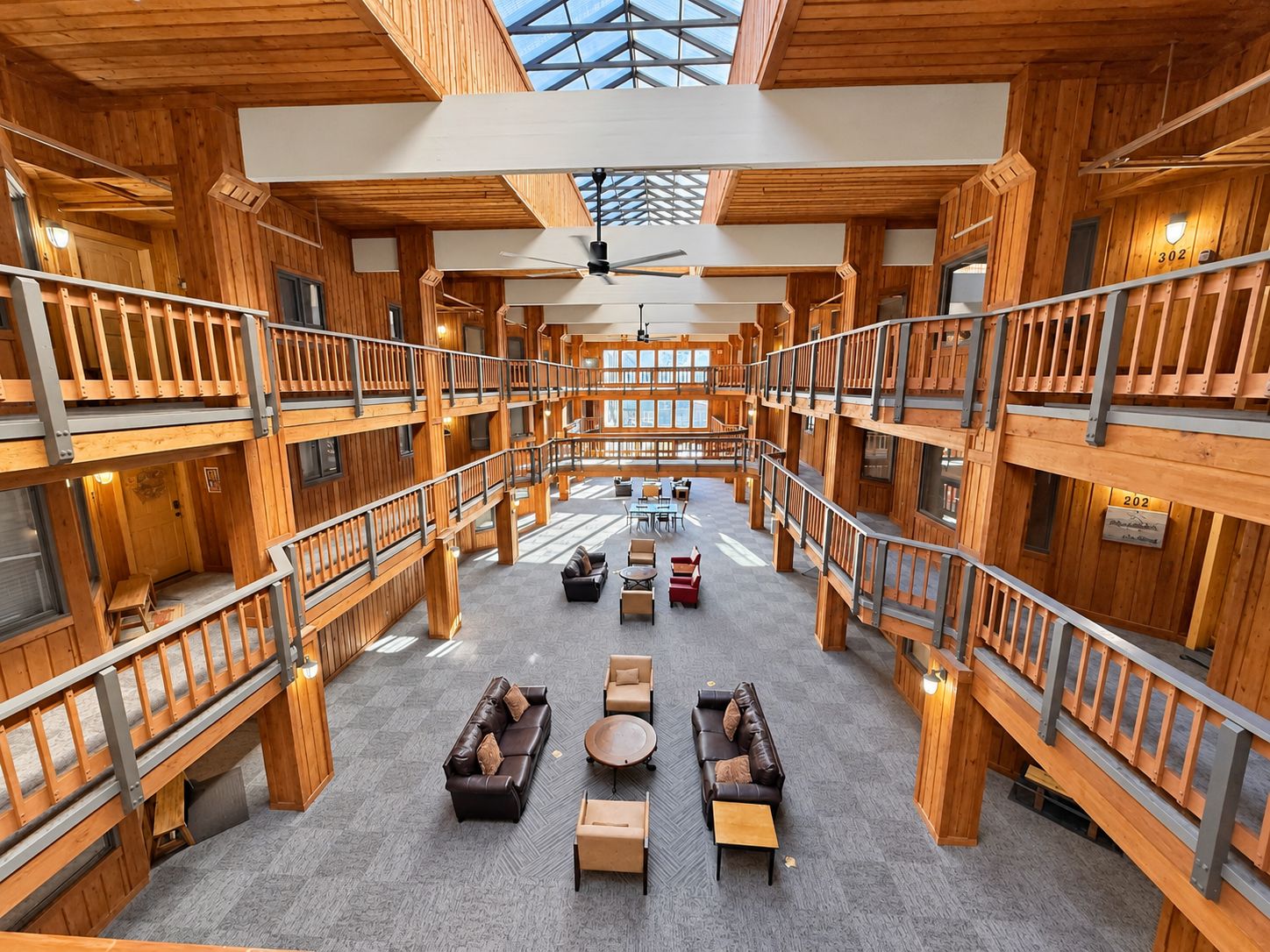 A multi-level wooden interior with a central open space, railings, and seating areas.
