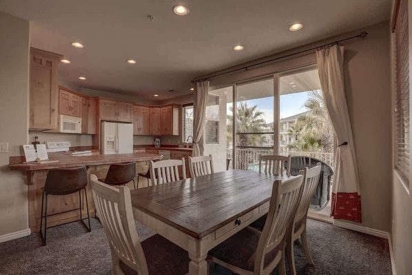 A kitchen with wooden cabinets, a dining table, and chairs.