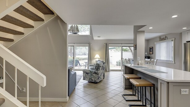 Een moderne keuken met een centraal eiland, barkrukken en een eethoek met stoelen.
