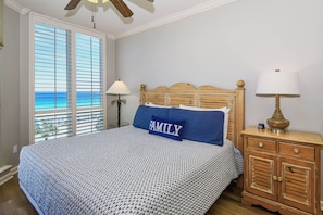 A bedroom with a bed, a nightstand, a lamp, and a view of the ocean through the window blinds. - Comfortable Beachfront Condo w/ Easy Beach Access in Central Destin! 🏖☀🌴 (Destin)