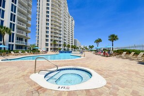 A hotel pool area with a hot tub, lounge chairs, and a large building in the background. - Comfortable Beachfront Condo w/ Easy Beach Access in Central Destin! 🏖☀🌴 (Destin)