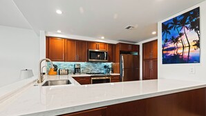 Una cocina moderna con armarios de madera, un refrigerador de acero inoxidable y un microondas.