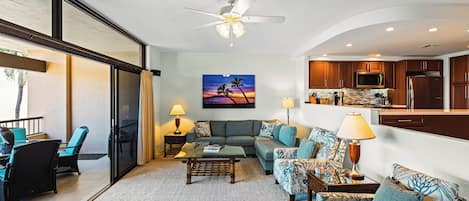 A modern living room with a sectional sofa, a coffee table, and a view of the kitchen.