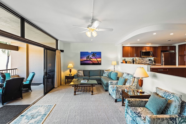 A modern living room with a sectional sofa, a coffee table, and a view of the kitchen.