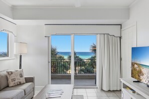 Una habitación con balcón, sofá, mesa de centro y televisor.