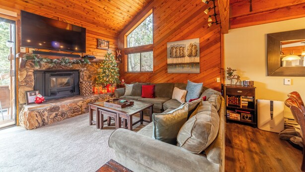 Ein gemütliches Blockhaus-Interieur mit Kamin, einem großen Flachbildfernseher, einer bequemen Sitzecke und einem Weihnachtsbaum.