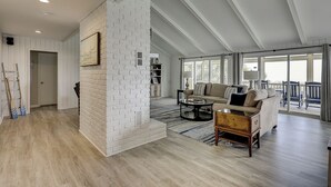 A spacious living area with a white brick accent wall, a sofa set, a coffee table, and a view to a balcony.