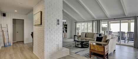 A spacious living area with a white brick accent wall, a sofa set, a coffee table, and a view to a balcony.