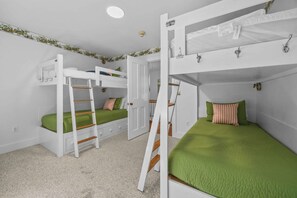 Een slaapkamer met stapelbed, een ladder, een deur en een plafondlamp.