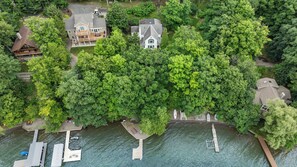 An aerial view of a residential area with houses, a dock, and a small boat. - Great Adventure: Family Fun Starts Here! (Keuka Park)