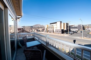 A balcony with wicker furniture overlooking a street with buildings and mountains in the background. - Heart of Downtown Durango - Pet Friendly Condo with Views - AC (Durango)