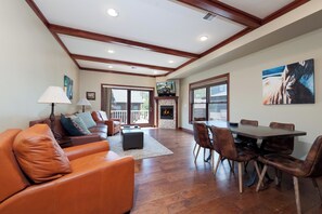 A spacious living area with a fireplace, a dining table with chairs, and a large window providing a view of the outdoors. - Heart of Downtown Durango - Pet Friendly Condo with Views - AC (Durango)