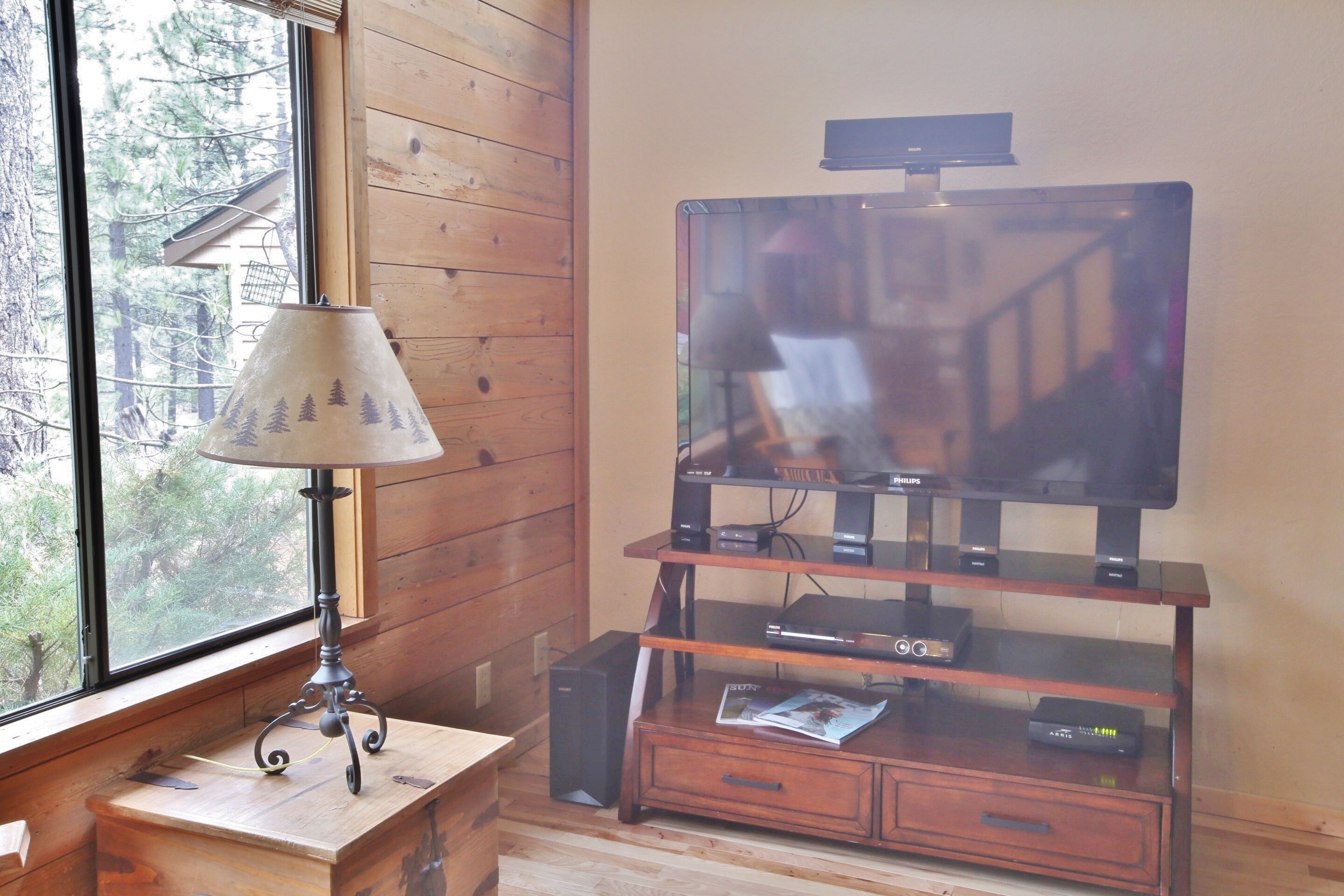 Un interior de madera con un televisor sobre un mueble de madera, una lámpara y un pequeño armario.