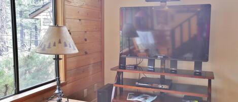 Un interior de madera con un televisor sobre un mueble de madera, una lámpara y un pequeño armario.