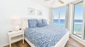 Una camera da letto con un letto, un comodino, una ventola a soffitto e vista sull'oceano.