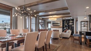 A spacious dining area with a large table and chairs, a fireplace, and a view of the outside. - Ultra Luxury + Pool + Slopeside - Snowline Ridge (Steamboat Springs)