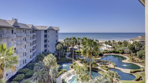 A resort with multiple swimming pools, a beach, and a large building with balconies.