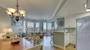 A spacious kitchen with a dining area, wooden flooring, and a view to the outside.