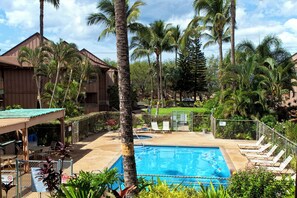 A pool area with lounge chairs and a building with a sloped roof.