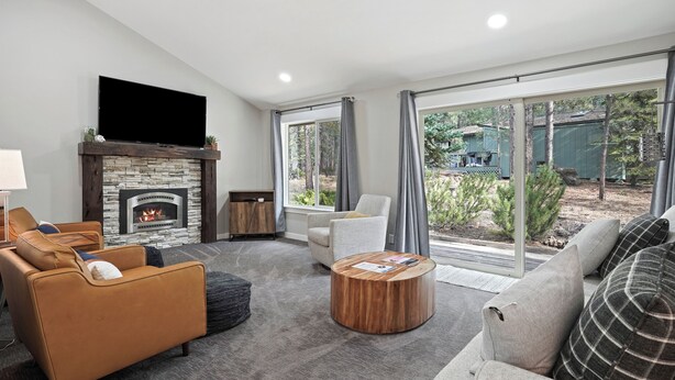 Una sala de estar moderna con chimenea, asientos cómodos y ventanas amplias que ofrecen vistas al exterior.