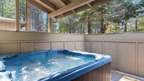Un jacuzzi en una terraza de madera con vistas a árboles.