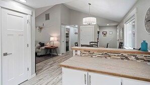Una cocina moderna con encimera de madera, armarios blancos y una lámpara colgante.