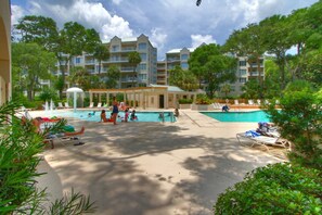 Relax by the pool surrounded by lush greenery and palm trees.