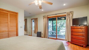 A bedroom with a bed, a dresser, a television, and a sliding glass door leading to an outdoor area. - The Willows:"Delightful Cottage with Peaceful Sunsets" (Lodi)