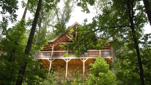 Una cabaña de madera con varios balcones, rodeada de un bosque denso.