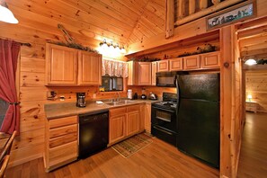 Cocina estilo cabaña de madera con armarios de madera, microondas integrado, refrigerador, cafetera y lavavajillas.