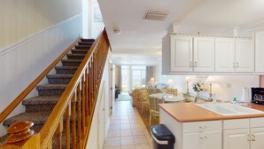 A staircase with wooden railings leading to a living area with a sofa and a dining table.