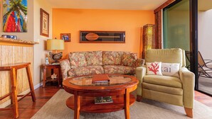 Una sala de estar con sofá, sillón, mesa de centro redonda y estantería.