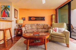 Una sala de estar con sofá, sillón, mesa de centro redonda y estantería.