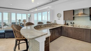 Une cuisine moderne dotée d’un îlot central aux lignes courbes, de meubles en bois foncé et d’une grande fenêtre offrant une vue sur la ville.