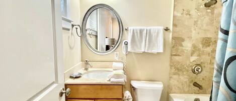 Un baño con lavamanos, espejo, inodoro y ducha.