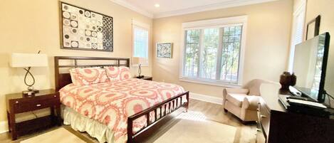 A bedroom with a bed, a desk, a chair, a ceiling fan, and a window.
