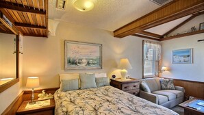 Una camera da letto con un letto, un divano, un comodino, una lampada e un quadro appeso al muro.
