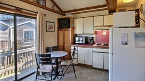 Un angolo cottura compatto con zona pranzo, frigorifero, microonde e macchina del caffè.