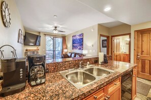 A modern kitchen with granite countertops, stainless steel appliances, and a large window overlooking a deck. - Free SkyCard Activities - Gas Fireplace, Parking, Equipped Kitchen, Fitness Ctr (Breckenridge)