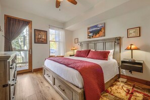 A bedroom with a bed, a nightstand, a lamp, a window with curtains, a door, and a ceiling fan. - Free SkyCard Activities - Gas Fireplace, Parking, Equipped Kitchen, Fitness Ctr (Breckenridge)